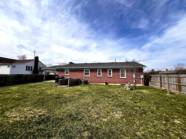 rear view of property featuring cooling unit, brick siding, a fenced backyard, and a lawn