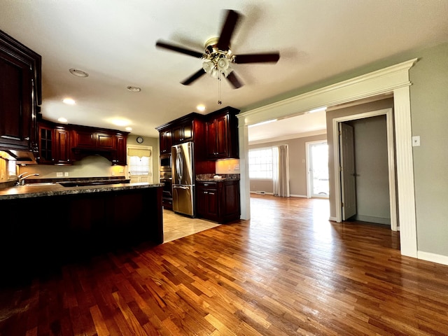 kitchen featuring a ceiling fan, freestanding refrigerator, glass insert cabinets, light wood-style floors, and dark countertops