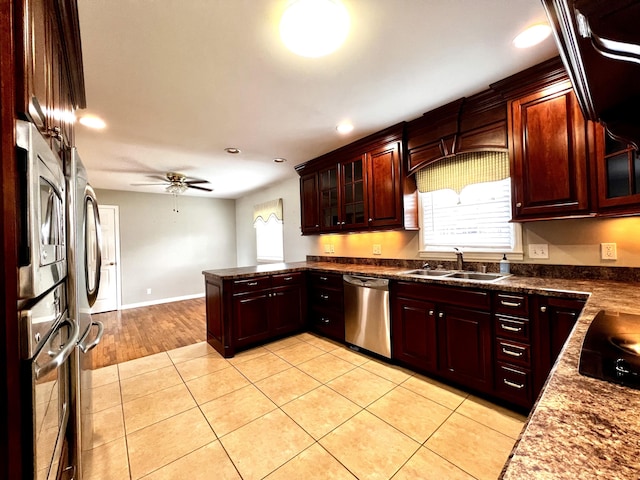 kitchen with a ceiling fan, a peninsula, light tile patterned flooring, a sink, and appliances with stainless steel finishes