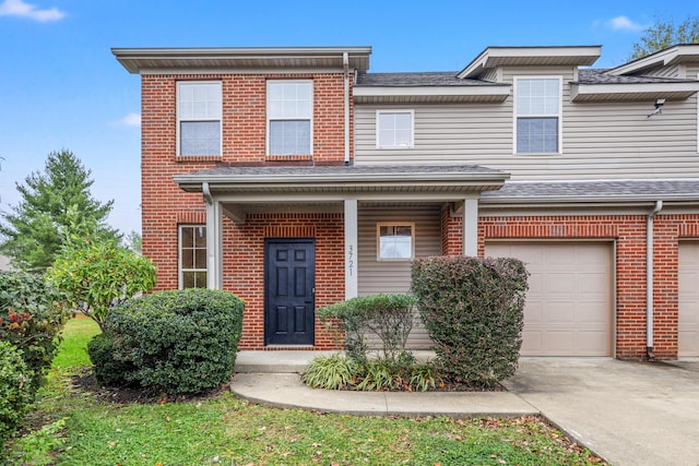 view of property with a garage, brick siding, and driveway