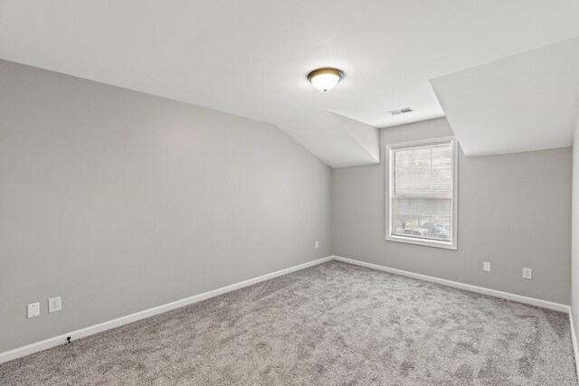 additional living space featuring visible vents, baseboards, carpet, and vaulted ceiling