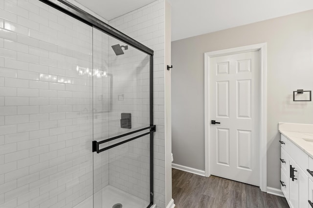 full bath featuring baseboards, wood finished floors, a stall shower, and vanity