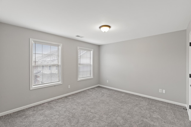 empty room featuring carpet, visible vents, and baseboards