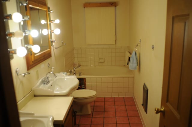 full bath with tile patterned flooring, toilet, vanity, and tiled bath