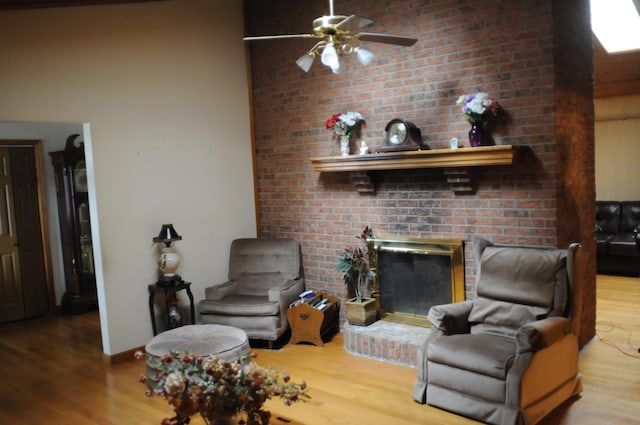 living room featuring ceiling fan, baseboards, wood finished floors, and a fireplace