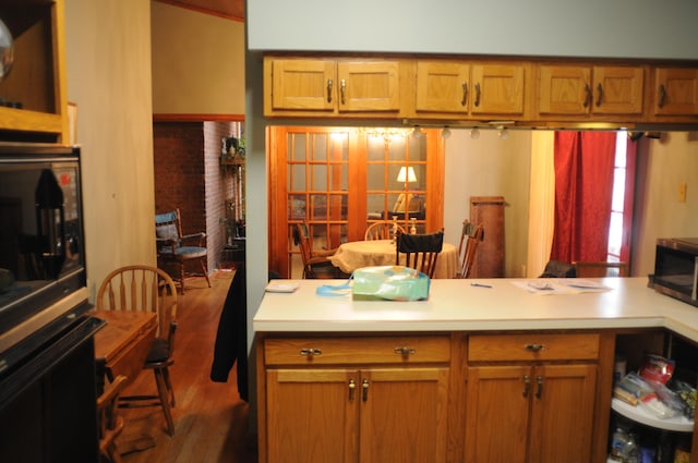 kitchen featuring light countertops, stainless steel microwave, wood finished floors, and brown cabinets