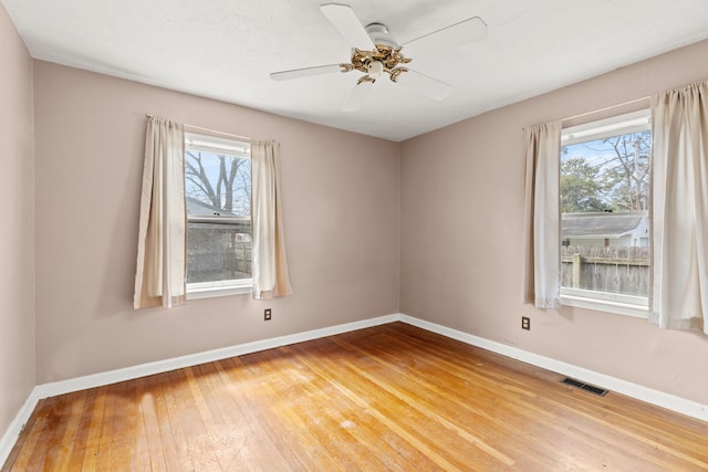 empty room with plenty of natural light, light wood-style floors, and baseboards