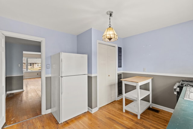 kitchen with visible vents, baseboards, stainless steel range with gas stovetop, light wood-style flooring, and freestanding refrigerator