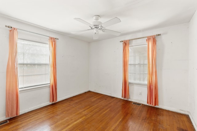 empty room with visible vents, ceiling fan, and hardwood / wood-style flooring