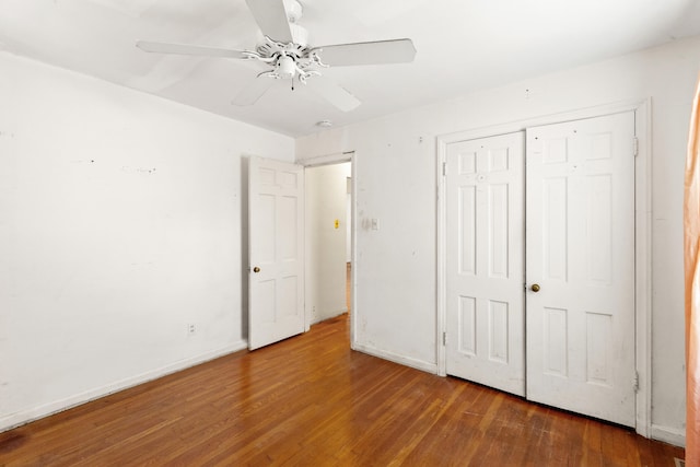 unfurnished bedroom featuring a closet, baseboards, wood finished floors, and a ceiling fan