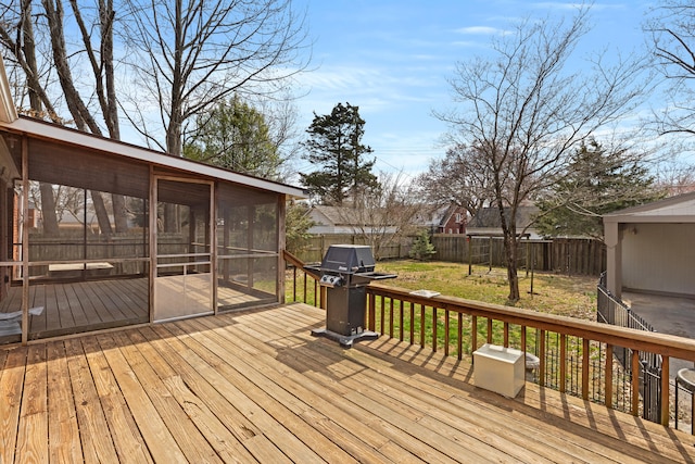 wooden terrace featuring a fenced backyard, a lawn, a sunroom, and a grill