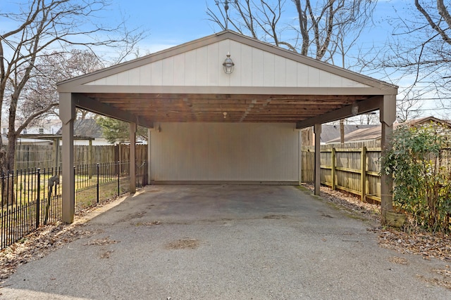 view of vehicle parking featuring aphalt driveway, a carport, and fence