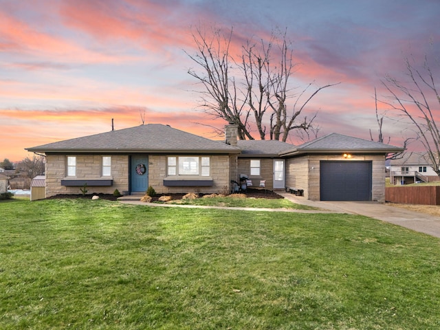 view of front facade with a yard, stone siding, an attached garage, and driveway