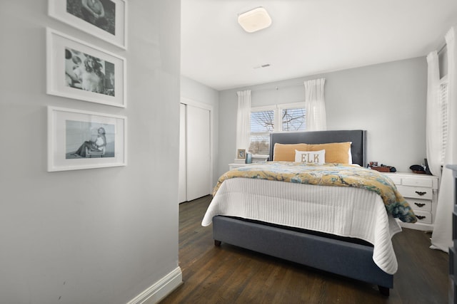 bedroom with visible vents, dark wood-style flooring, a closet, and baseboards