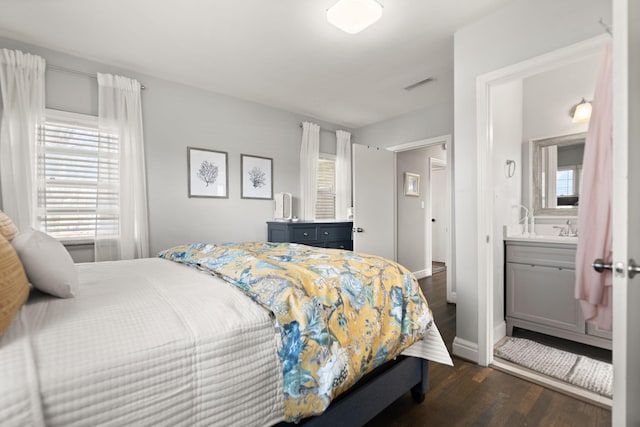 bedroom featuring dark wood finished floors, ensuite bath, multiple windows, and visible vents