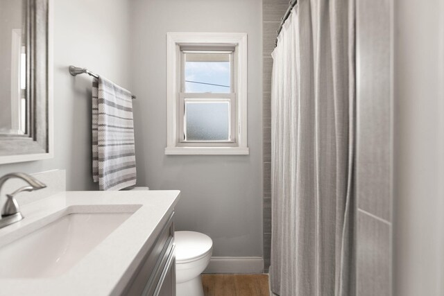 bathroom featuring vanity, wood finished floors, baseboards, curtained shower, and toilet