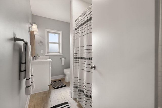 full bathroom with baseboards, toilet, a shower with shower curtain, wood finished floors, and vanity