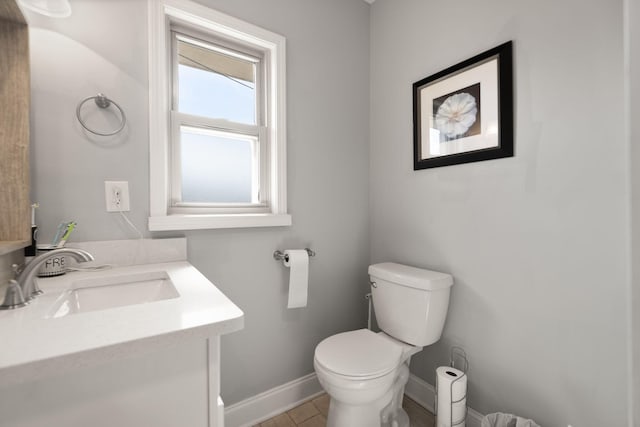 half bathroom featuring baseboards, toilet, and vanity