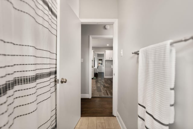 corridor with light wood-style floors and baseboards