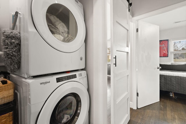 laundry room with visible vents, dark wood-type flooring, laundry area, and stacked washing maching and dryer