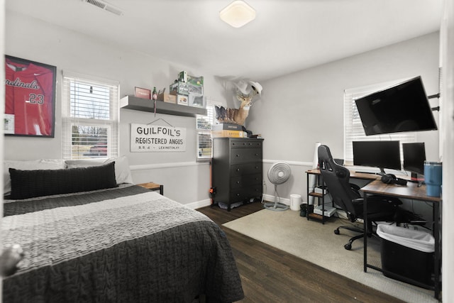 bedroom with dark wood finished floors, baseboards, and visible vents