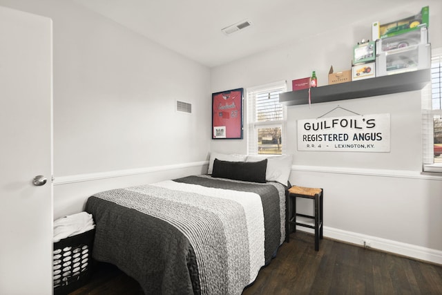 bedroom with wood finished floors, visible vents, and baseboards