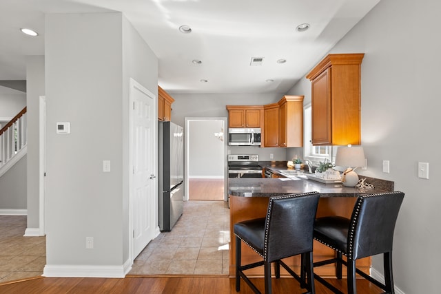 kitchen with visible vents, baseboards, a sink, appliances with stainless steel finishes, and a peninsula