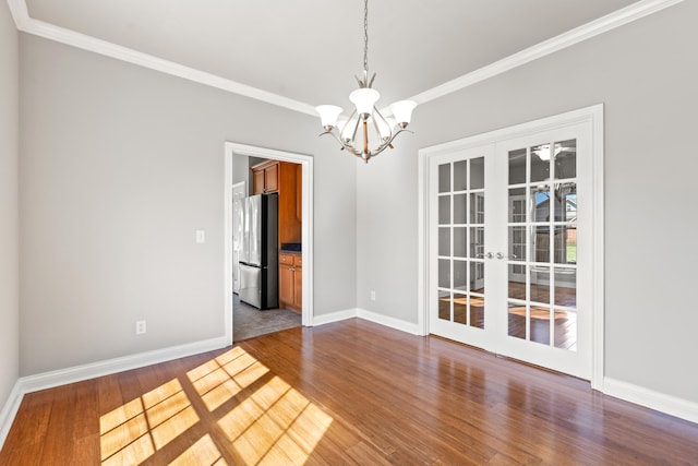 unfurnished dining area featuring french doors, baseboards, a notable chandelier, and wood finished floors