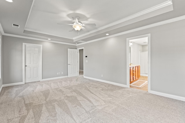 unfurnished room with visible vents, baseboards, a ceiling fan, a tray ceiling, and light colored carpet
