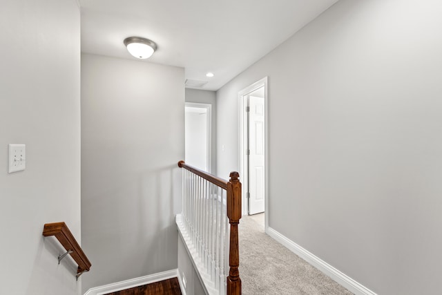 hall with recessed lighting, an upstairs landing, baseboards, and dark carpet