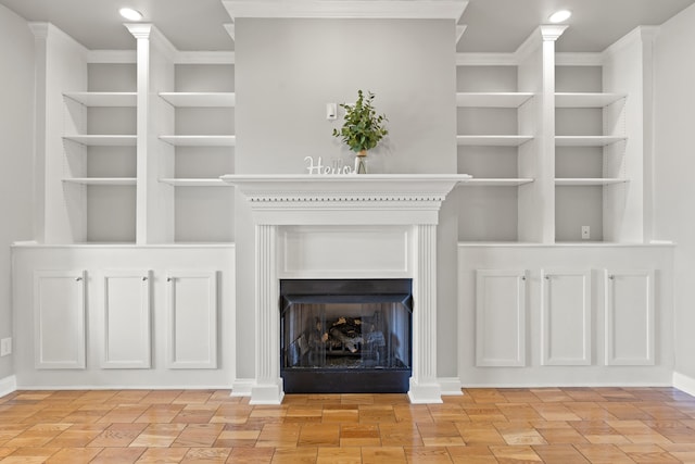 unfurnished living room featuring crown molding, built in features, and a fireplace