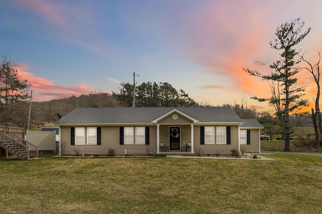 ranch-style home featuring covered porch and a yard