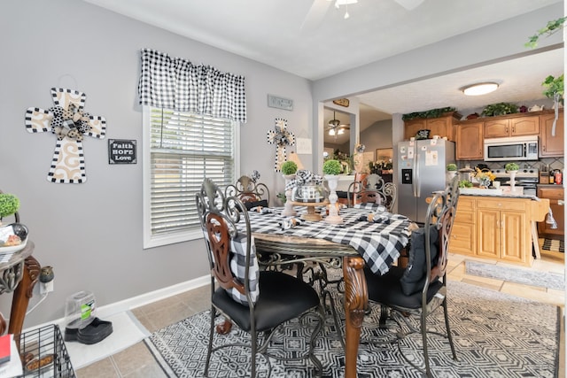 dining space with baseboards, ceiling fan, and light tile patterned flooring