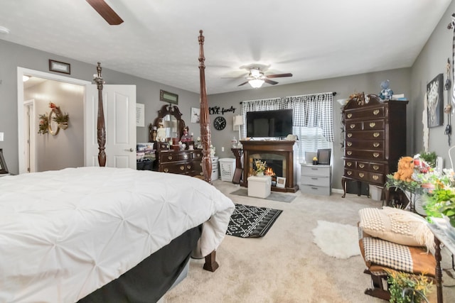 bedroom featuring carpet flooring, a warm lit fireplace, and ceiling fan