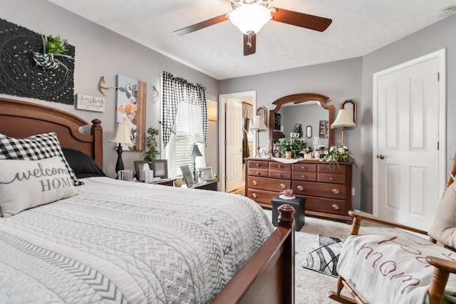 bedroom with a textured ceiling, light colored carpet, and ceiling fan