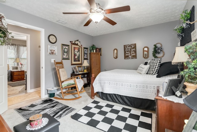 bedroom featuring visible vents, baseboards, a textured ceiling, and a ceiling fan