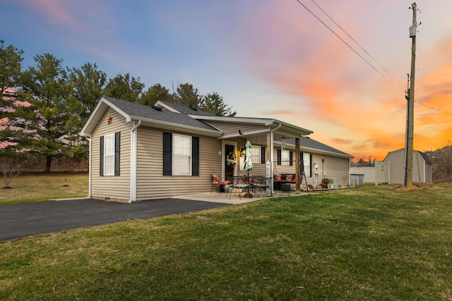 back of house at dusk with a yard, a shed, a patio, and an outdoor structure