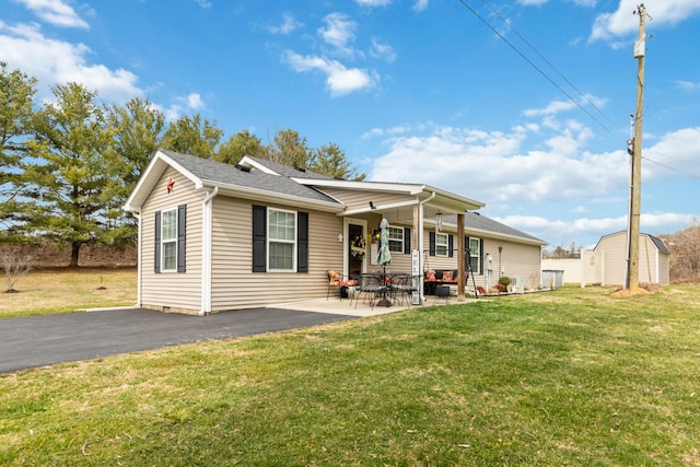 back of house featuring an outbuilding, a patio area, a storage shed, and a yard