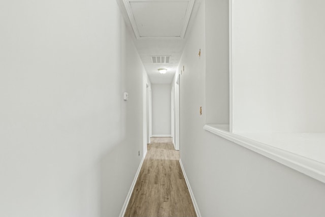 corridor featuring light wood-style flooring, baseboards, and visible vents