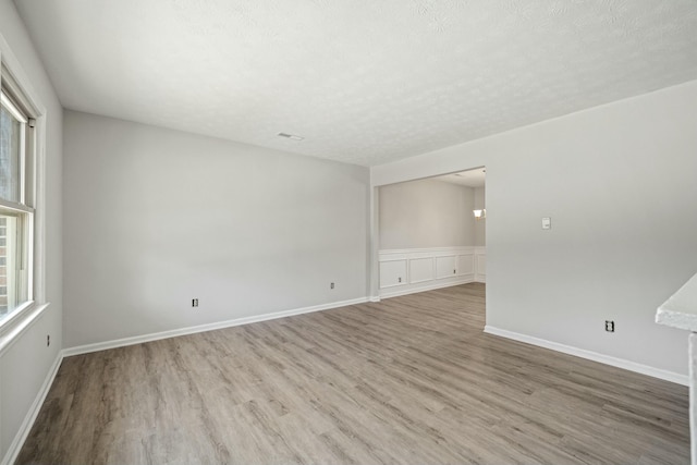 unfurnished room with baseboards, a textured ceiling, and wood finished floors