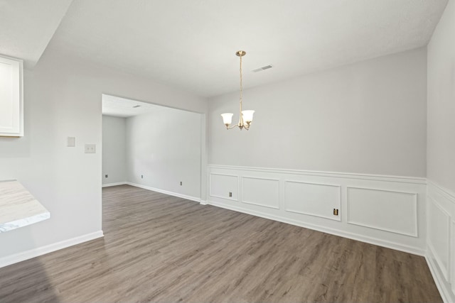 spare room with wood finished floors, visible vents, and a chandelier