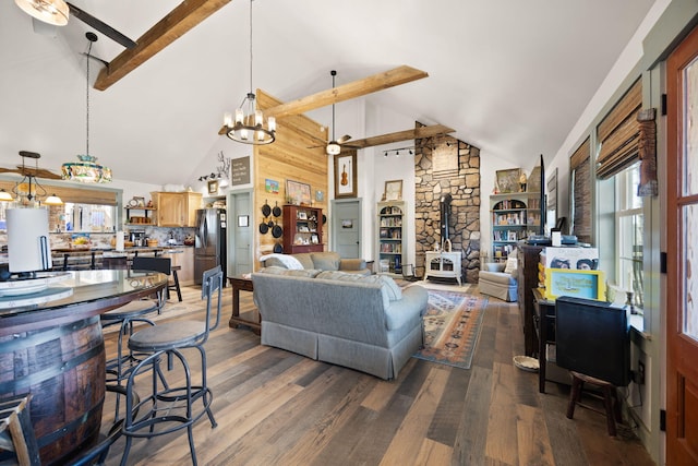 living room featuring beam ceiling, a wood stove, wood finished floors, and a chandelier