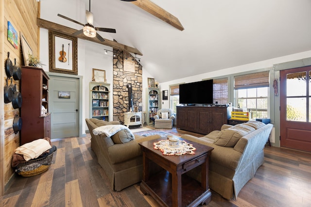 living room featuring ceiling fan, beamed ceiling, wood finished floors, and a wood stove