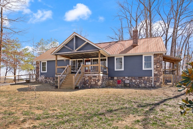 view of front of property with a front yard, stairway, fence, a chimney, and metal roof