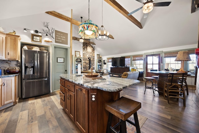 kitchen featuring stainless steel fridge, dark wood finished floors, light stone countertops, and ceiling fan with notable chandelier