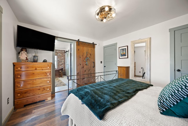 bedroom featuring a barn door, wood finished floors, and baseboards