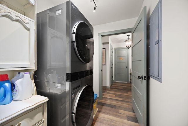 washroom with cabinet space, wood finished floors, and stacked washer / dryer