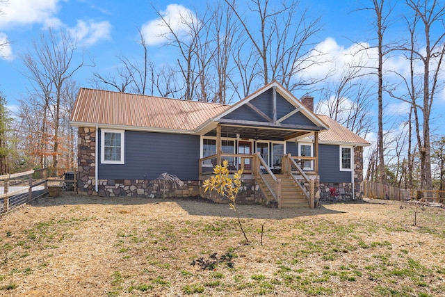 rear view of house with a chimney, stairway, metal roof, and fence