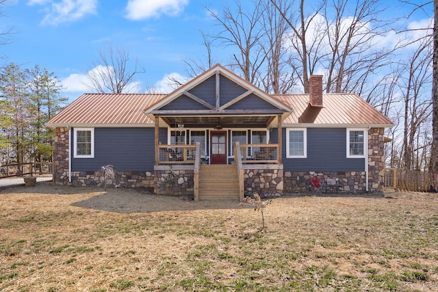 view of front facade featuring a front yard, covered porch, a chimney, metal roof, and crawl space