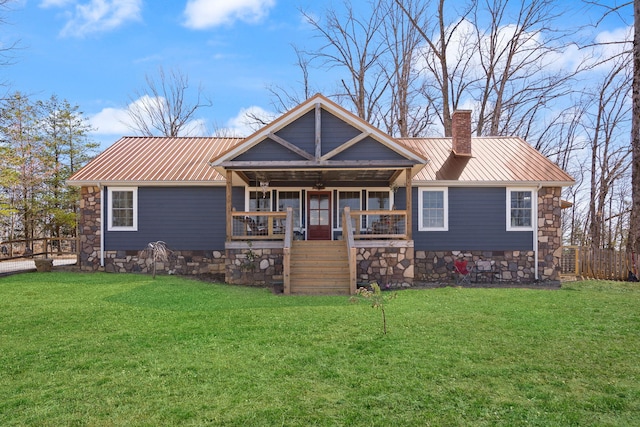 view of front of home featuring a porch, a front yard, a chimney, metal roof, and stone siding